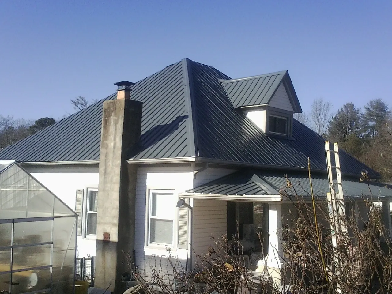 Dark blue standing seam metal roof on a white farmhouse with dormer — Slate & Tile Roof Repair by Roofing Brothers in Pequea