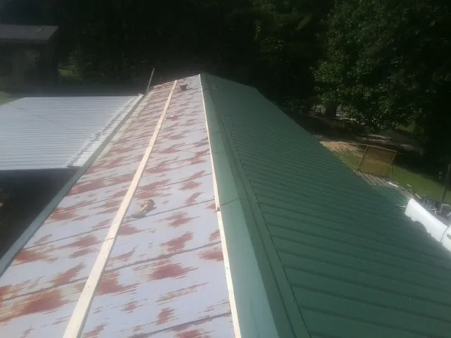 Old rusted panels beside newly installed green metal roofing — Wind Damage Roof Repair by Roofing Brothers in Pequea
