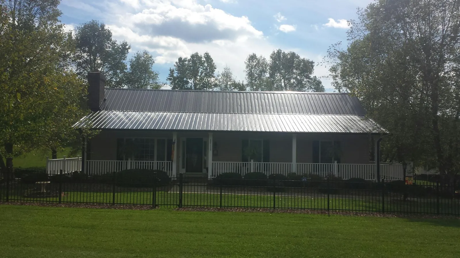 Gray metal roof on a brick ranch with a full width front porch — Gutter Guard Installation work by our crew in Pequea