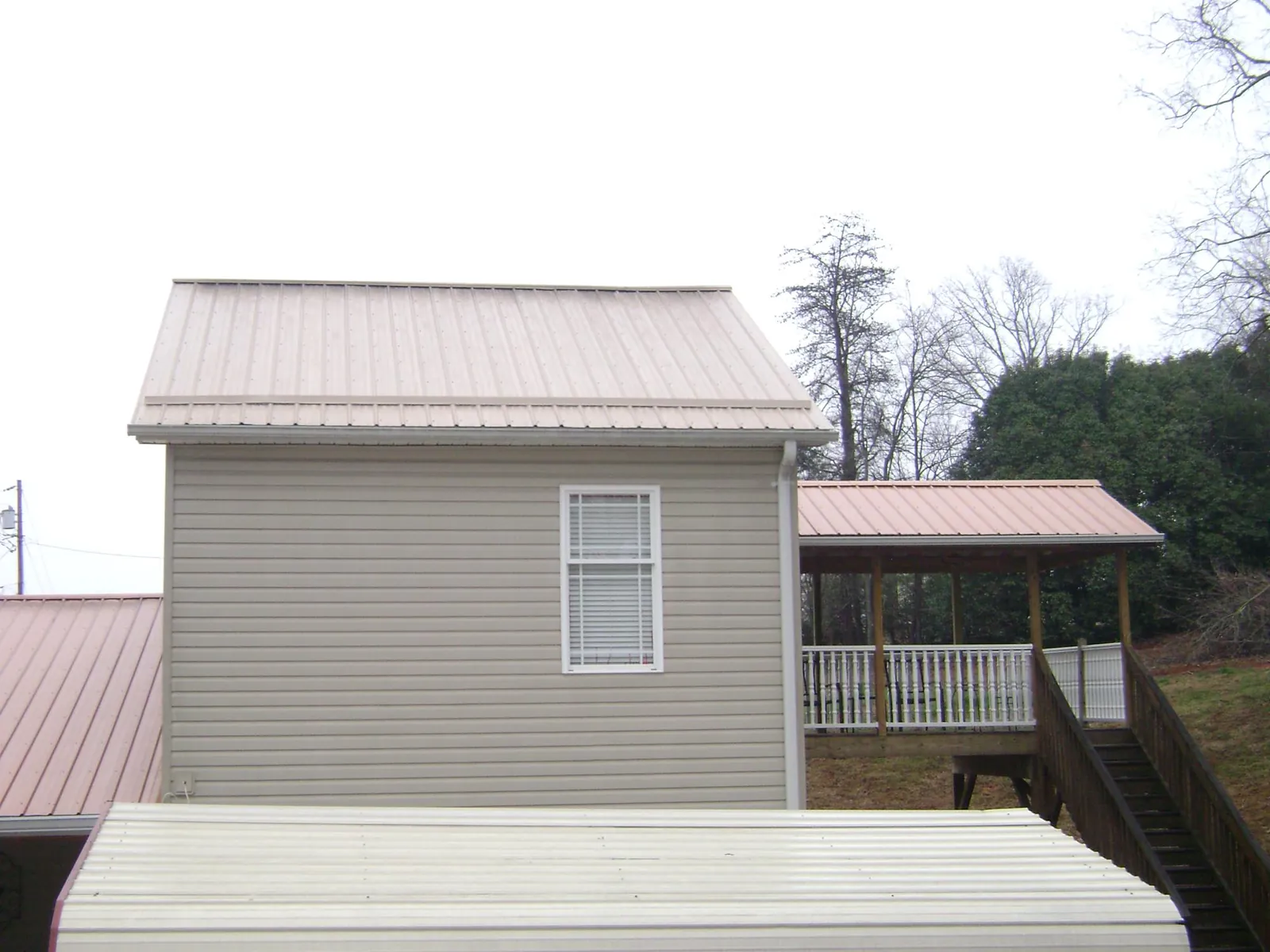 Tan metal roofs on a two story addition and attached porch, from a Roof Replacement job in Pequea