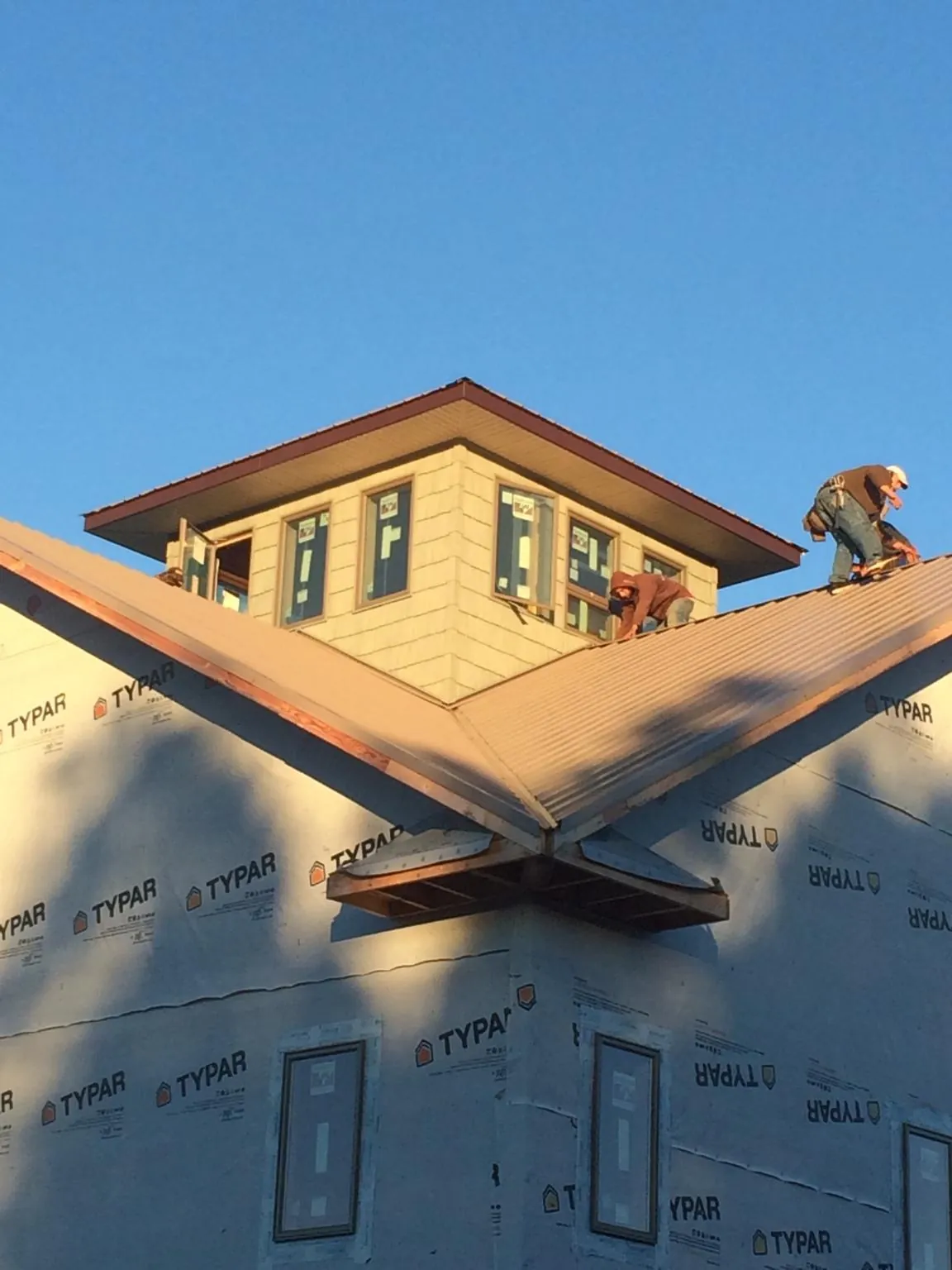 Roofers working around a rooftop cupola on a new metal roof at sunset — Roof Waterproofing in Pequea by Roofing Brothers